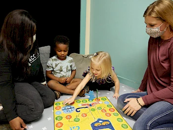 Small children playing a game with their speech therapists.
