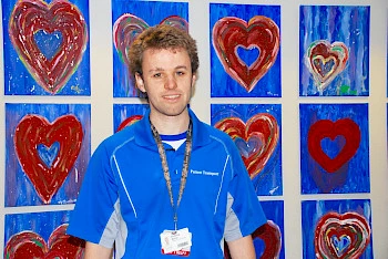 Young man standing in front of a wall of heart artwork