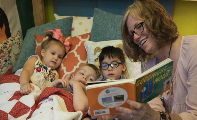 Adult woman reading to children in classroom.